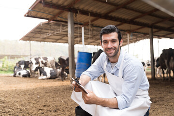 agriculture industry, dairy farming, livestock and animal husbandry concept. Dairy farmer male at cowshed on dairy farm. Male livestock veterinarian checking or health - obrazy, fototapety, plakaty