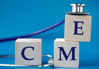 CME - acronym on wooden large cubes on blue background with stethoscope