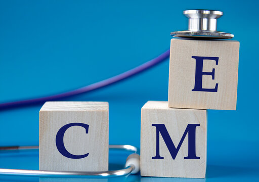 CME - acronym on wooden large cubes on blue background with stethoscope