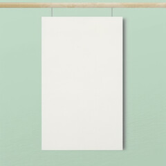 Empty poster template hanging on a soft colored wall.