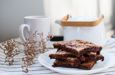 A little stacks of tasty sweet brownie with cherry on light background. Coffee and chocolate cake.