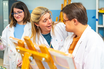 Art teacher talking to man with down syndrome while painting