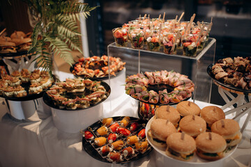 Food, a beautifully decorated catering banquet table with a variety of appetizers with cheese, ham, prosciutto and fruit. At a corporate, Christmas, birthday or wedding celebration. Buffet table. Buff
