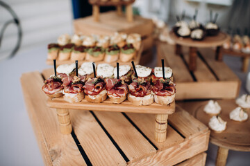 Food, a beautifully decorated catering banquet table with a variety of appetizers with cheese, ham, prosciutto and fruit. At a corporate, Christmas, birthday or wedding celebration. Buffet table. Buff