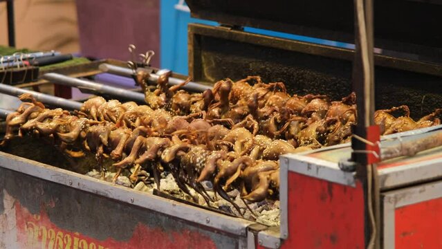 Chicks frying on the grill on an outdoor market. Traditional Thai street food concept