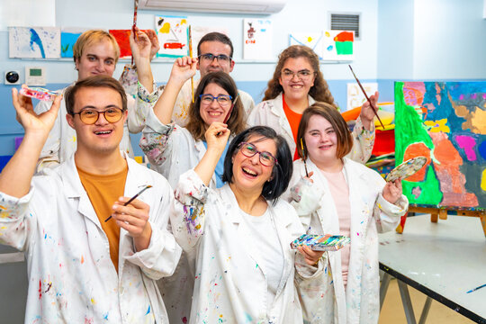 Happy disabled people with dirty coats in a painting class