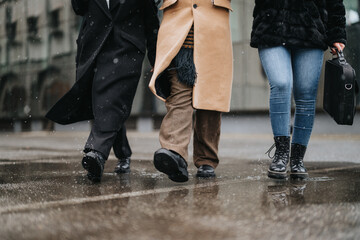 Partial view of business colleagues teamed up, braving the snowy weather as they walk down a city...