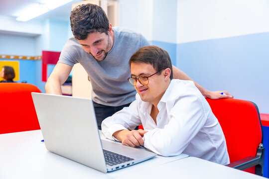 Teacher helping a man with down syndrome during computing class