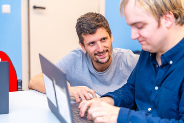 Teacher helping a disabled man during computing class