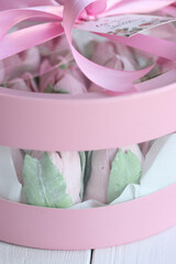 Zephyr in a box. Marshmallow tulips. The box is pink, tied with a ribbon. It stands on white boards. Close-up.aффa