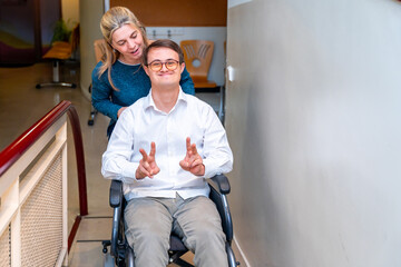 Health worker pushing a man with down syndrome using wheelchair - obrazy, fototapety, plakaty
