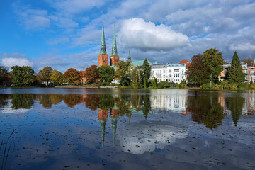 Lubeck, Germany. View of Lubeck Cathedral from the opposite shore of Muhlenteich (Mill pond) in autumn day. The cathedral was started in 1173 and consecrated in 1247. - 749544105