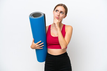 Young sport caucasian woman going to yoga classes while holding a mat isolated on white background...
