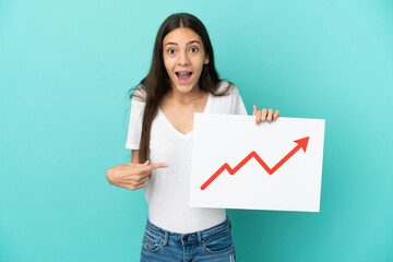 Young French woman isolated on blue background holding a sign with a growing statistics arrow...