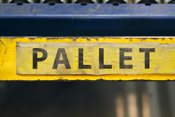 A yellow vibrant eye catching pallet loading bay sign. Storing stacks of wooden pallets. Yellow dock signs in a factory and warehouse setting. Industrial transportation.