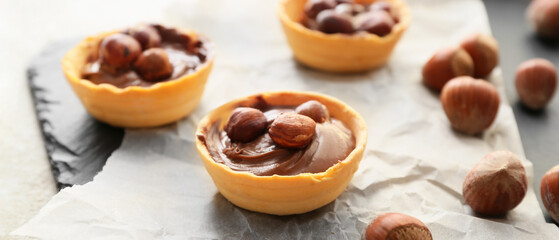 Tartlets with tasty chocolate paste and hazelnuts on table