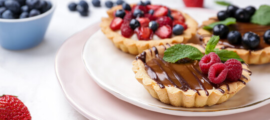 Sweet tartlets with berries on plate, closeup