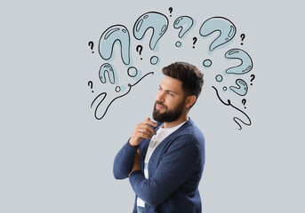 Thoughtful young bearded man on light background