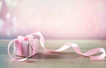 Gift box with bow and curved ribbon empty copy space background,holiday glowing backdrop. Women's...