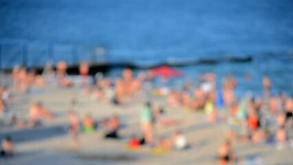 Many people relaxing on sandy beach of seashore and swimming in sea on hot sunny summer day. Many white-skinned people on sea public beach in summer. Rest vacation relax activity. Blurred background