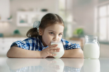 Little girl drinking glass of milk at kitchen indoors.Adorable kid have a dairy meal.Healthy...