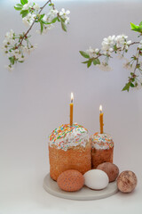Easter cakes with burning candles and eggs on white background