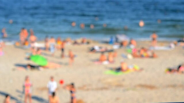 Many people relaxing on sandy beach of seashore and swimming in sea on hot sunny summer day. Many white-skinned people on sea public beach in summer. Rest vacation relax activity. Blurred background