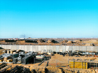 Fototapeta na wymiar A construction site with a large wall in the background. The sky is clear and blue. Scene is calm and peaceful