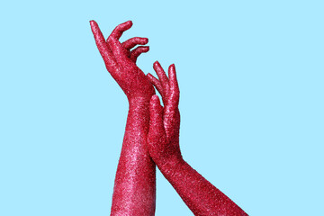 Female hands covered with glitter on color background, closeup