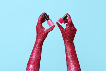 Painted female hands with bottles of nail polish on color background, closeup