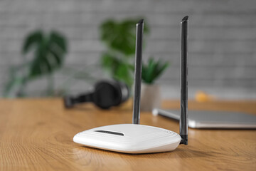Modern wi-fi router on wooden table in room, closeup
