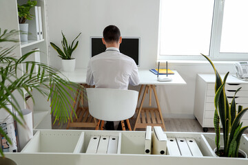 Businessman with wi-fi router working at table in office, back view - obrazy, fototapety, plakaty