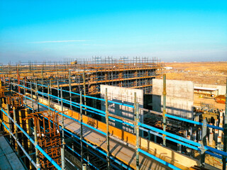 A construction site with scaffolding and a blue sky in the background. Scene is one of progress and hard work