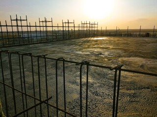 A construction site with a fence in the background. The fence is made of metal and is in the foreground