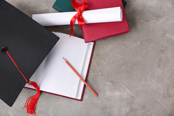 Mortar board with diploma and notebooks on grey background