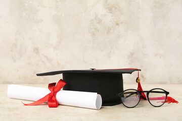 Mortar board with diploma and eyeglasses on beige background