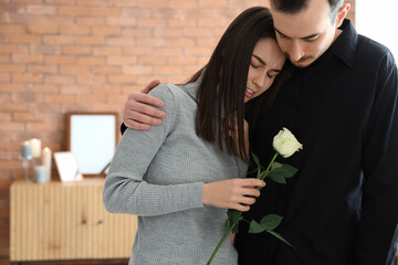 Mourning young couple with rose at funeral