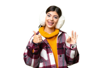 Young Russian woman wearing winter muffs over isolated chroma key background showing ok sign and thumb up gesture