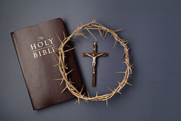 A symbolic Christian composition with Holy Bible lies beside a crown of thorns on a dark background...
