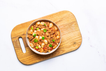 Tasty homemade chili con carne with chips on the wooden tray on white marble table top view.

