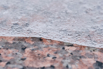 Melting ice partially covers granite tiles.