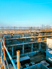 A construction site with scaffolding and a blue sky in the background. Scene is one of progress and hard work