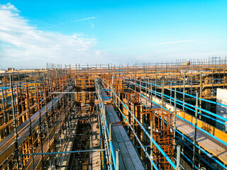 A construction site with scaffolding and a blue sky in the background. Scene is one of progress and hard work
