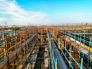 A construction site with scaffolding and a blue sky in the background. Scene is one of progress and hard work