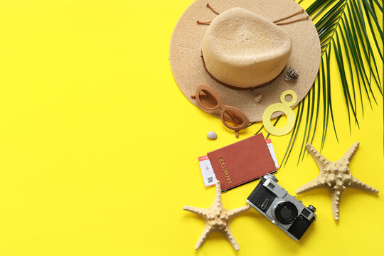 Composition with beach accessories, passport, photo camera and palm leaf on yellow background. International Women's Day
