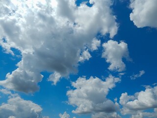Naklejka na ściany i meble Beautiful blue sky with fluffy white clouds, perfect for background or texture in design projects