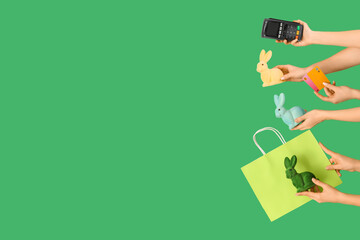 Women with payment terminal, credit cards, bag and Easter rabbits on green background. Online shopping