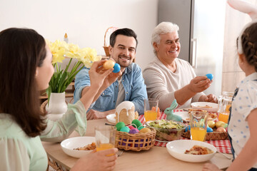 Happy family breaking Easter eggs at home