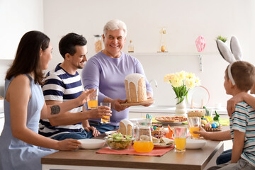 Mature man bringing Easter cake for dinner with his family in kitchen