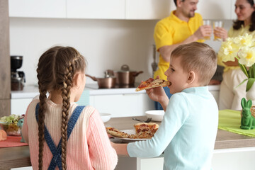 Fototapeta premium Little children with pizza having Easter dinner in kitchen